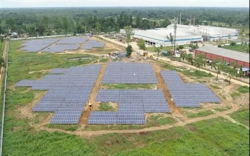 Ground-mounted solar panel array at an industrial site, representing large-scale commercial solar energy generation